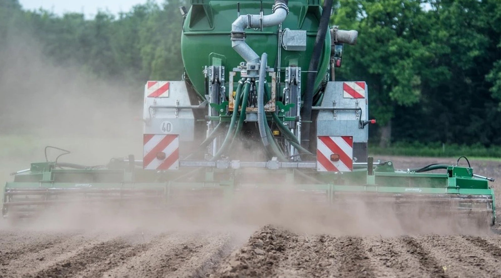 Tractor spreading liquid fertiliser across a ploughed field
